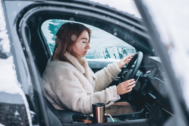 Attractive woman driver sitting behind the steering wheel in her car