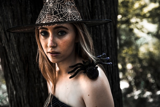 Attractive woman in hat and artificial spider on shoulder