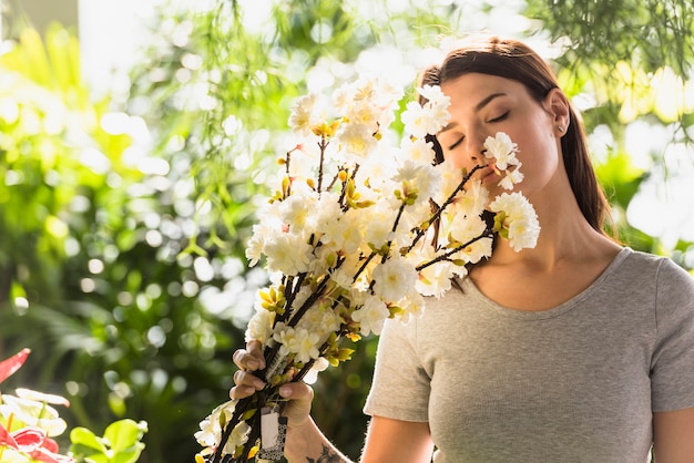 Attractive woman holding bunch of flower twigs near face