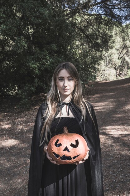 Attractive woman holding pumpkin in park 