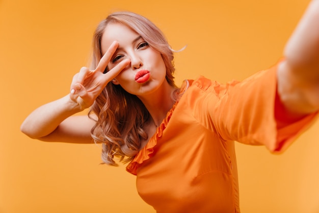 Attractive woman in orange dress making selfie