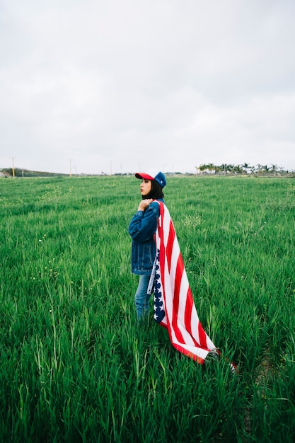 Free photo attractive woman staying in summer field with flag