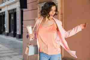 Free photo attractive woman in stylish outfit walking in city, street fashion, spring summer trend, smiling happy mood, wearing pink jacket and blouse, spinning around, exited, fashionista on shopping