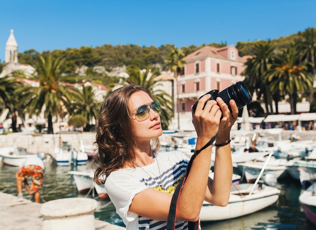 Free photo attractive woman on vacation in europe by the sea on a cruise taking pictures on camera