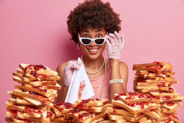 Free photo attractive woman with afro hair surrounded by peanut butter jellly sandwiches