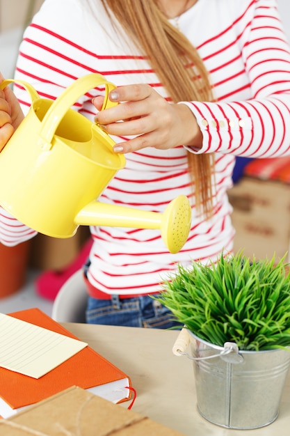 Attractive woman with grass with watering can