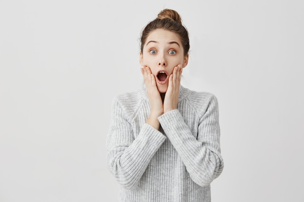 Attractive woman  with open mouth being shocked. Female student grabbing face being astonished about exam result. Education concept