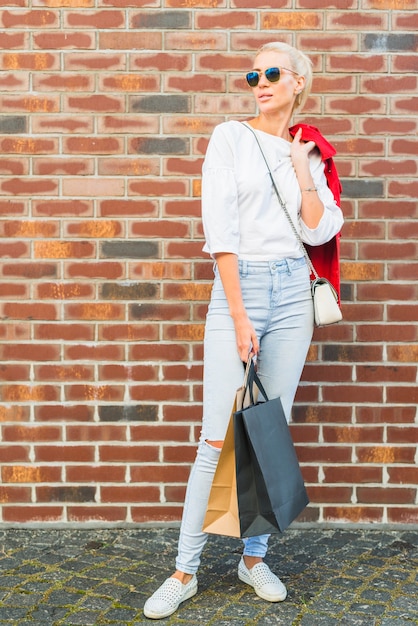 Free Photo attractive woman with packets near wall