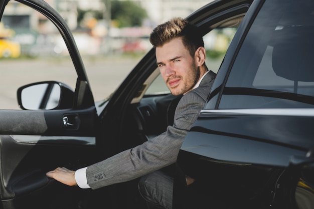 Free photo an attractive young businessman looking out from car