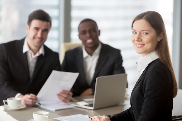 Attractive young businesswoman looking at camera, female team le