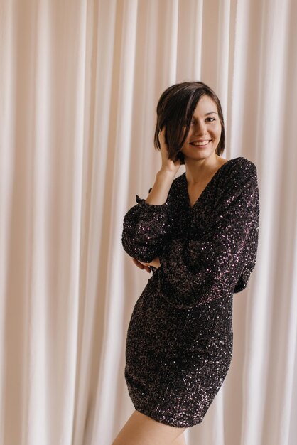 Attractive young caucasian brunette woman with bob haircut in black dress posing on white background Lifestyle concept