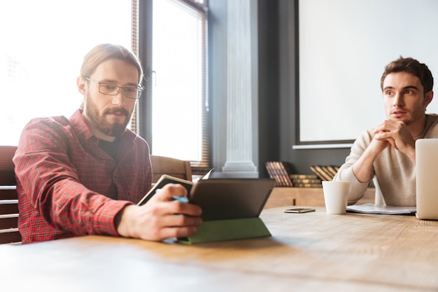 Free photo attractive young colleagues sitting in office