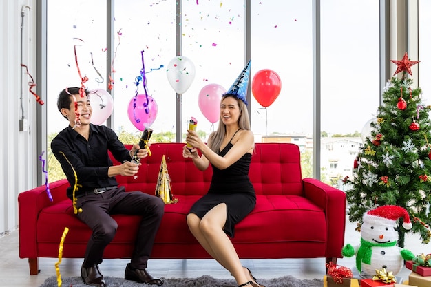 Free photo attractive young couple celebrate christmas new year together with confetti party popper and decorated christmas tree and presents