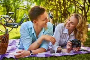 Free photo the attractive young couple using a compact photo camera at a picnic in a park.