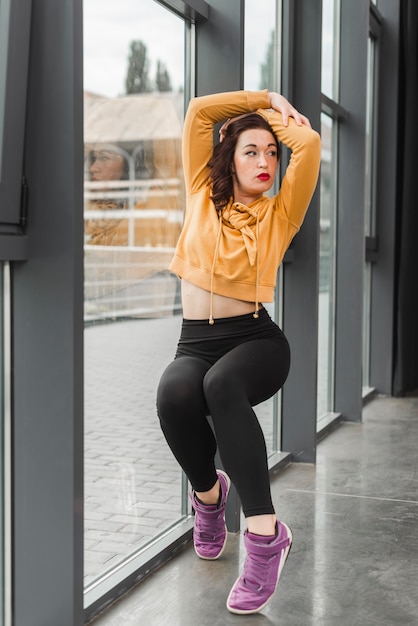 Attractive young female dancer posing in front of window