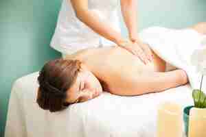 Free photo attractive young hispanic woman getting a back massage from a female therapist at a spa