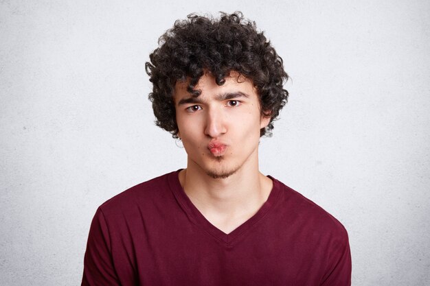 Attractive young male with crisp dark hair keeps mouth round