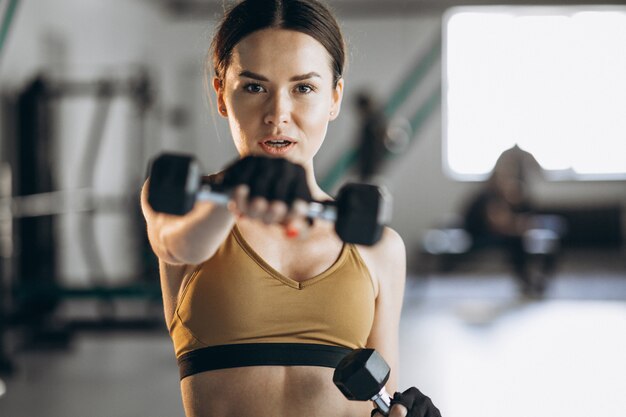 Attractive young woman exercising with dumbbells at the gym