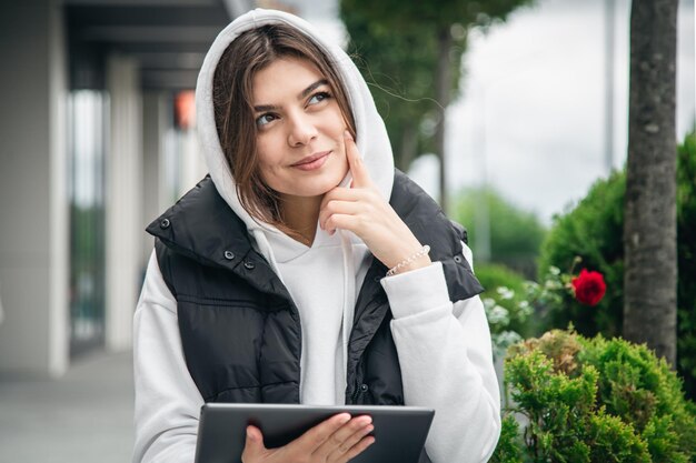 Attractive young woman holding a tablet outside