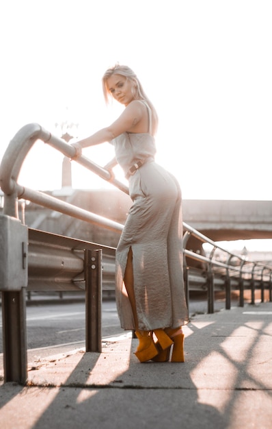 Attractive young woman is standing on promenade at bright sunny day.