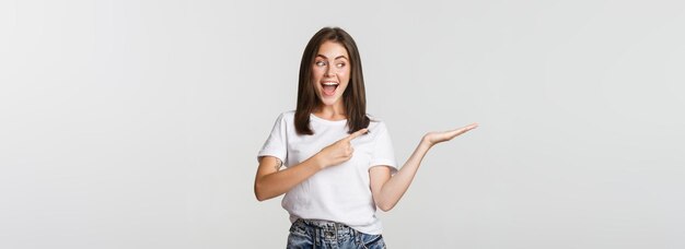 Attractive young woman pointing finger at something she holding on hand