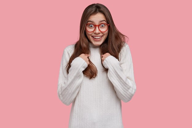 Attractive young woman points at herself, asks about something, dressed in casual jumper