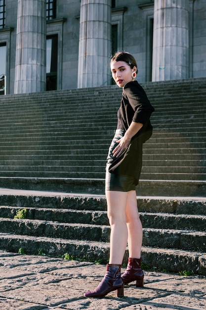 An attractive young woman posing in front of staircase with hand on hips