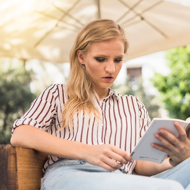 Attractive young woman reading book at outdoors