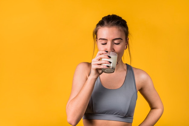 Attractive young woman in sportswear drinking milk