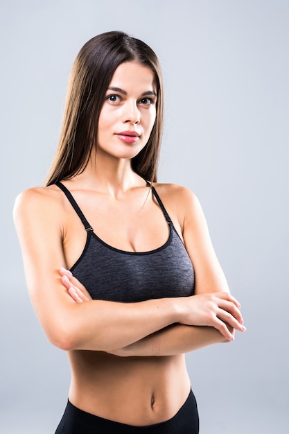 Attractive young woman in sportswear posing on grey.