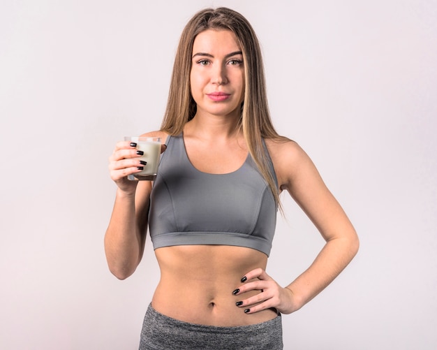 Free photo attractive young woman in sportswear with glass of milk