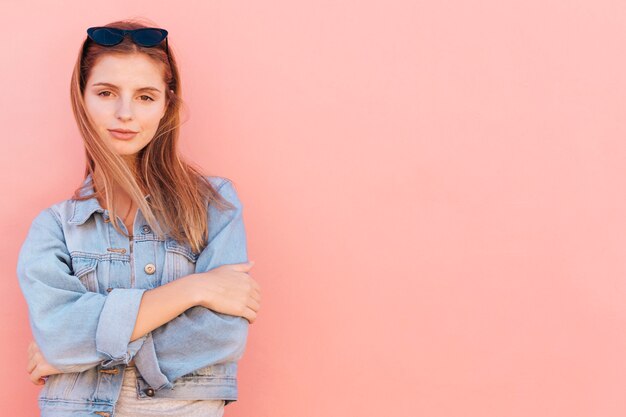 An attractive young woman standing against peach background