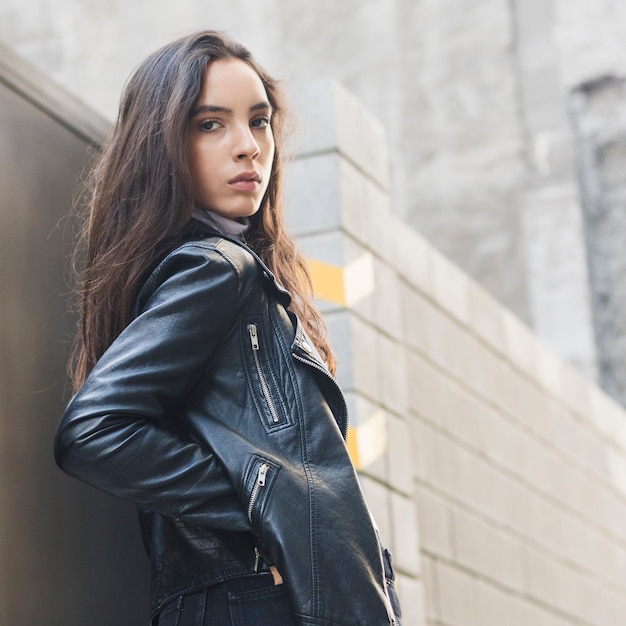 An attractive young woman with her hands in pocket looking at camera