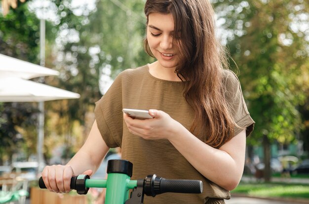 Attractive young woman with a rental electric scooter on a sunny day