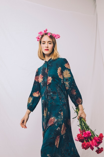 Attractive young woman with wreath on head and bouquet of flowers