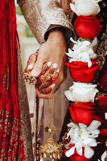 Free photo authentic indian bride and groom's hands holding together in traditional wedding attire