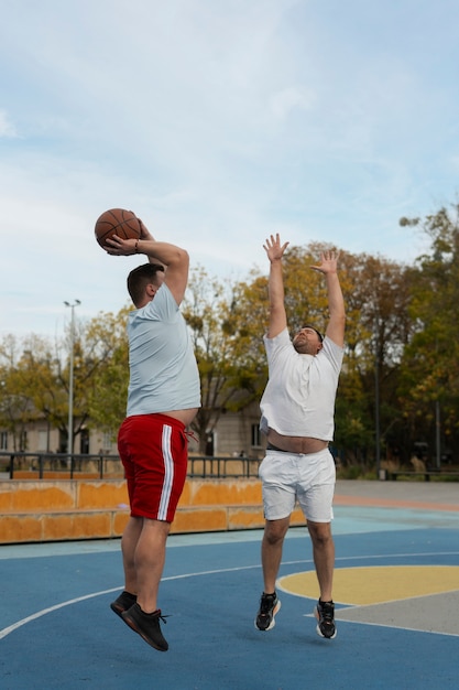 Authentic scenes of plus-size males playing basketball