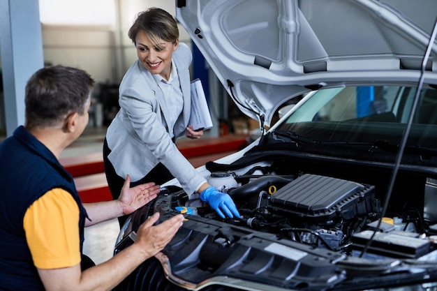 Free Photo auto mechanic and businesswoman cooperating while checking under vehicle hood in a workshop