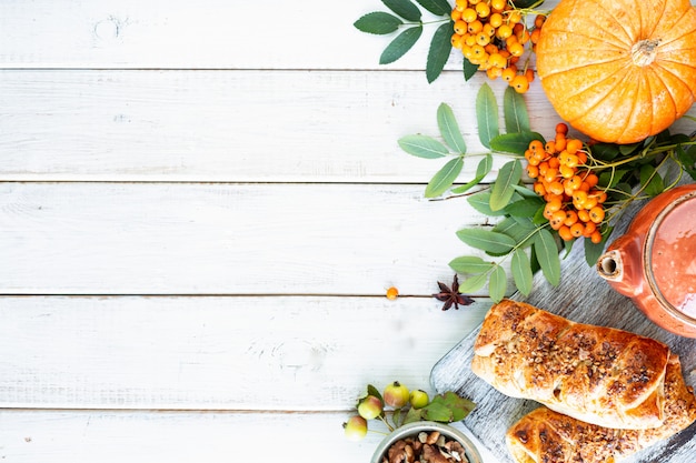 Autumn background. Apples, pumpkin, apples of paradise, rowan on a white wood. Top view.