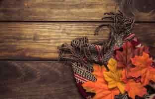 Free photo autumn composition of warm scarf and leaves