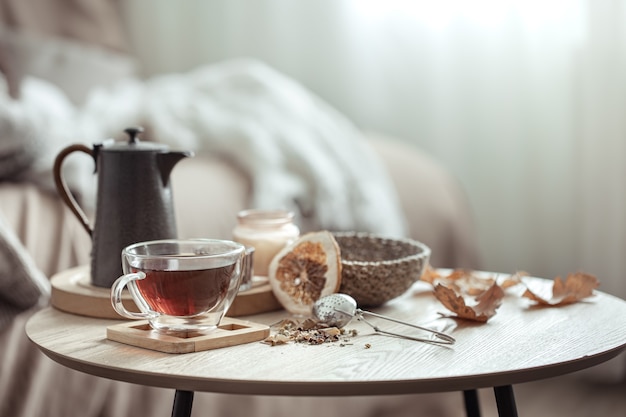 Autumn composition with a cup of tea, a teapot and autumn home decor details on a blurred background.