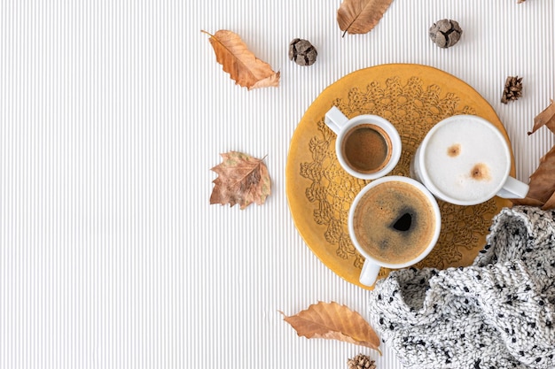 Autumn composition with cups of coffee and leaves on a white background