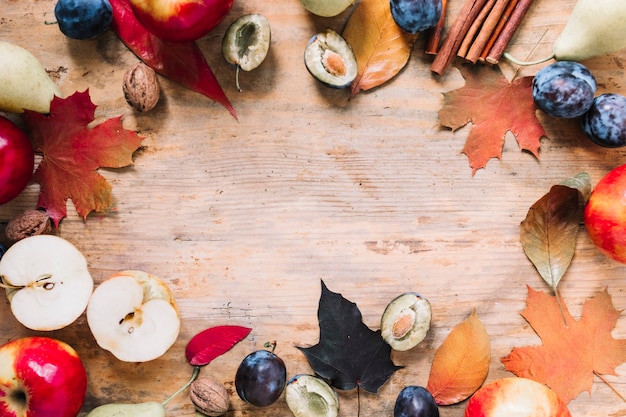 Autumn frame with leaves and fruit on wooden background