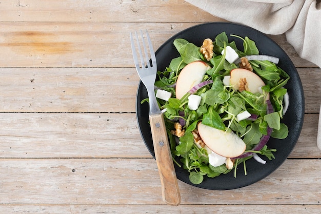 Autumn salad with apples and walnuts on wooden table