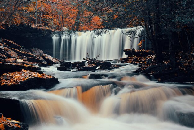 Autumn waterfalls in park with colorful foliage.