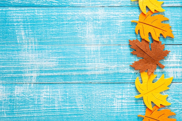 Free photo autumn wooden background with colored felt leaves