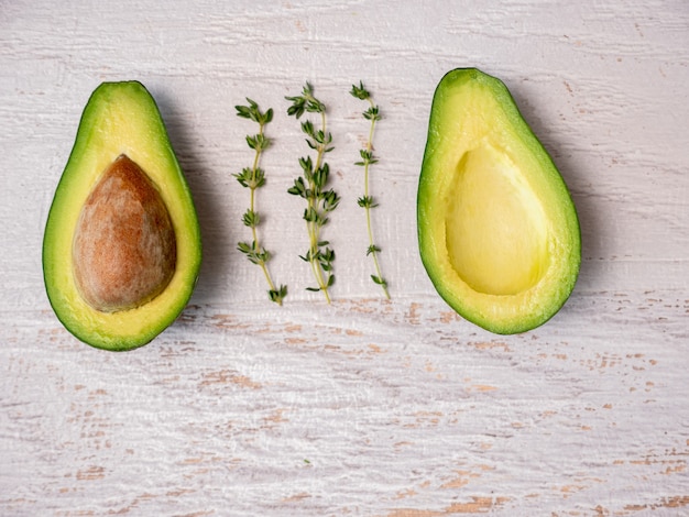 Avocado cut in half on white wooden board.