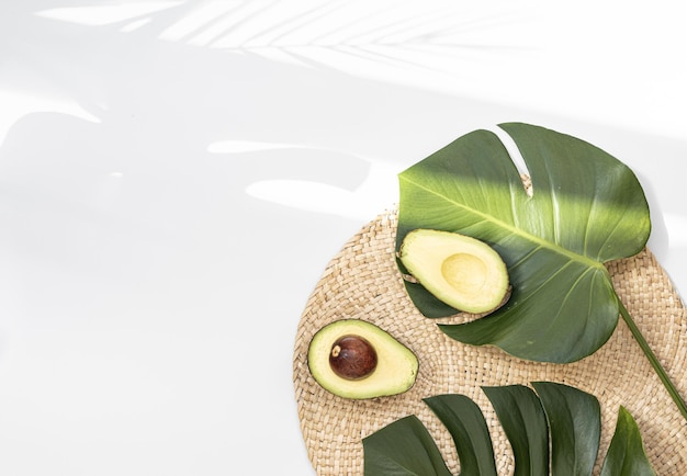 Free photo avocado pieces on a natural fibers floor and has a background of nature tropical monstera leaf