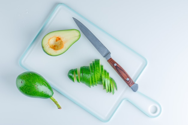 Free photo avocados with knife flat lay on white and cutting board