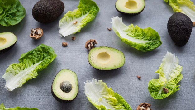 Avocados with lettuce scattered on table